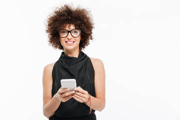 Smiling attractive businesswoman in eyeglasses holding mobile phone