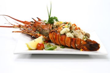 Stir-fried Lobster with Garlic & Butter Sauce on white square porcelain plate Isolated on white background with shadow, Low angle Side view, Luxury Seafood. Selective Focus at front