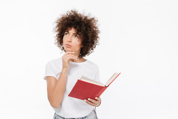 Pensive young woman holding book and looking away