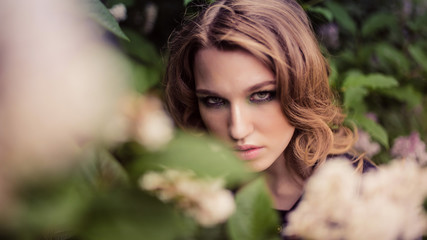 Fototapeta premium Portrait of relaxed young lady in a summer park waiting. Beautiful young girl with blonde curly hair , outdoor.