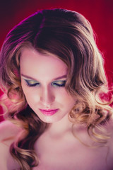Fototapeta premium Beautiful young girl with blonde curly hair red background