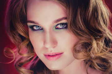 Fototapeta premium Beautiful young girl with blonde curly hair red background