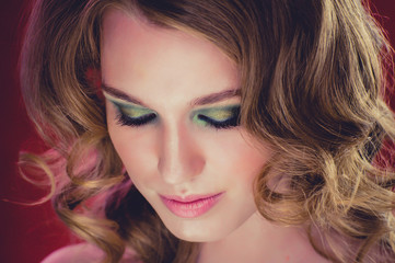 Naklejka premium Beautiful young girl with blonde curly hair red background