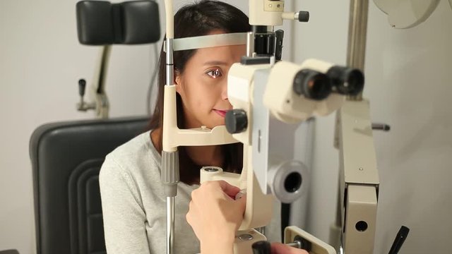 Woman checking vision with tonometer at optical clinic