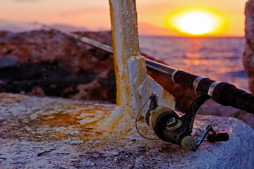 Fishing rod on a concrete at purple sunset