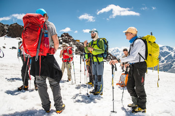 A team of climbers led by a guide discusses the upcoming ascent