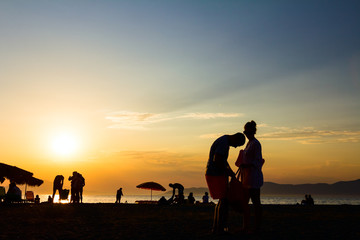 Obraz premium Silhouetted shot of sunset with people by the beach
