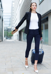 Adult female in suit with suitcase is going to the hotel