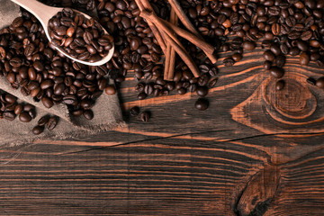 Wooden spoon with coffee beans on wooden table background with c