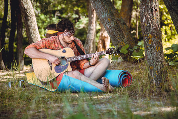 Beautiful young couple in love in hippie style rest on the nature. A man plays the guitar and the girl plays the drum