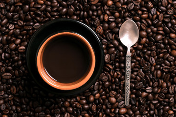 A cup of black coffee with coffee bean as background