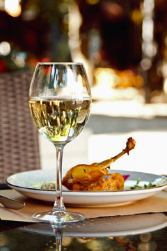 Duck leg config with sauce and glass of white wine in restaurants