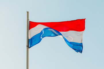 Fototapeta na wymiar Waving colorful Netherlands flag on blue sky