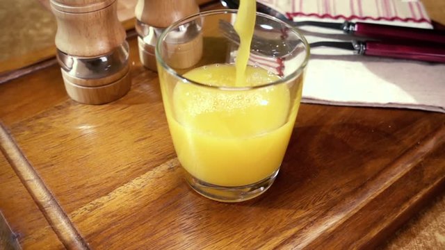 Orange juice pouring into a glass, the morning Breakfast. Slow motion with rotation tracking shot.