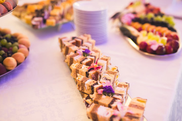 Delicious and tasty dessert table with cupcakes shots at reception closeup