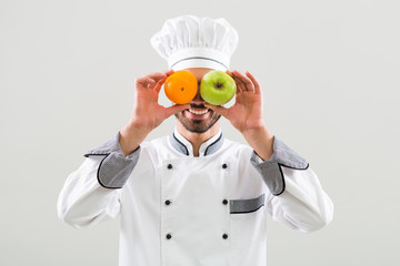 Chef is having fun with fruit on gray background.