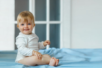 Fototapeta premium Smiling baby girl sit on the bed