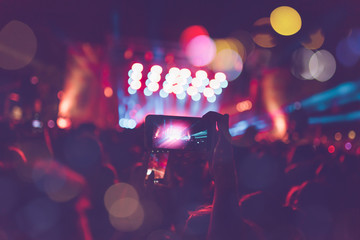 Silhouettes of festival concert crowd in front of bright stage lights. Unrecognizable people and...