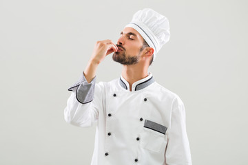 Chef is showing delicious sign on gray background.