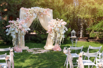 Wedding arch decorated with cloth and flowers outdoors. Beautiful wedding set up. Wedding ceremony...