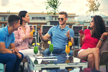 Friends having fun and drinking cocktails outdoor on a penthouse balcony