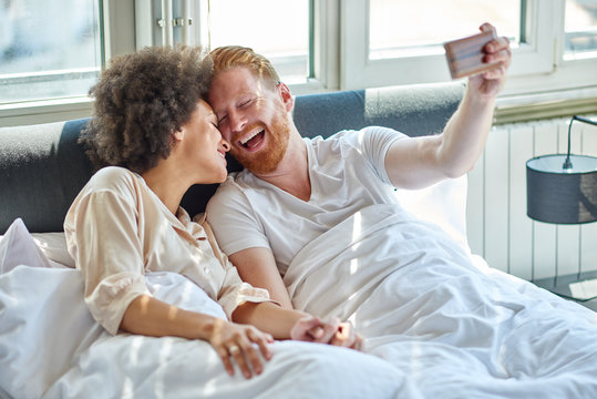 Young couple making selfie while lying in bed