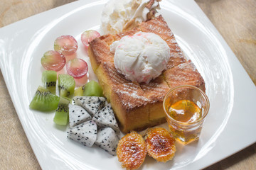 Honey toast on white dish with  banana, kivi, grape and icecream.