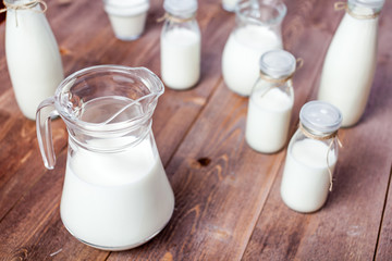 milk and glasses of milk on a wooden rustic table.