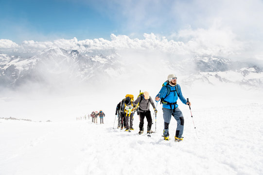 A group of mountaineers climbs to the top of a snow-capped mountain