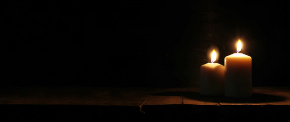 Burning candles over old wooden table with bokeh lights.