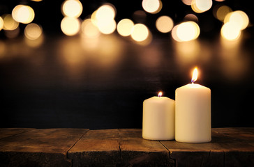 Burning candles over old wooden table with bokeh lights