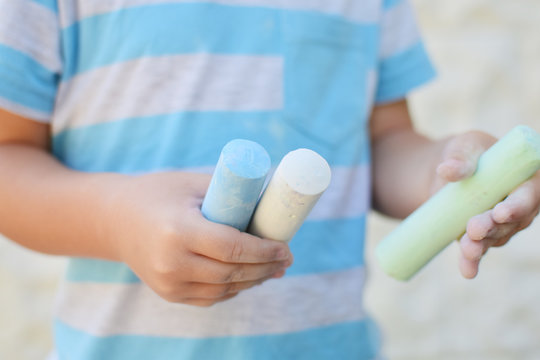 kid holding colored chalk paints for drawing