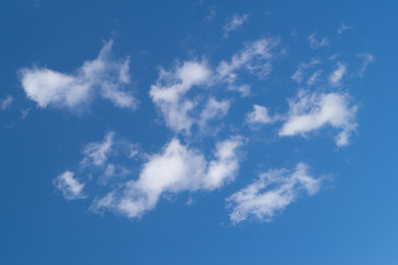 White fkuffy cumulus clouds on the bright blue sky