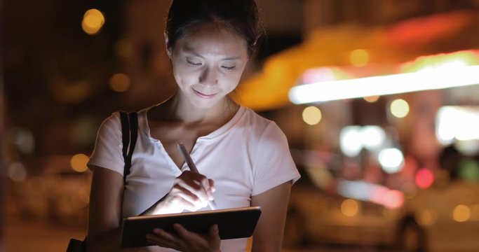 Woman using digital tablet with pen at night