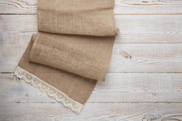 Canvas napkin with lace. Burlap hessian sacking on white wooden table background top view