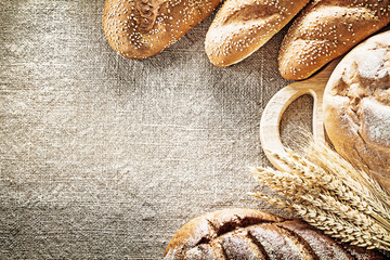 Brown bread breadstick chopping board rye ears on sacking backgr