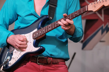 Obraz na płótnie Canvas musician guitarist in red jeans and a blue shirt