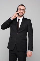 Half-length shot of young businessman in a suit talking on the phone and smiling