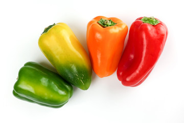 Green, red, yellow, orange bell peppers over white