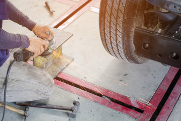 Electric wheel grinding on steel structure in auto repair shop