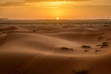 Fototapeta na wymiar Sunrise at Erg Chebbi sand dune of Sahara with ATV tyre markings on the sand, Merzouga, Morocco