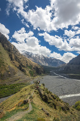 Fototapeta premium Beautiful view on impressive gorge in Caucasus mountains. Monument in form of Cross and path to it