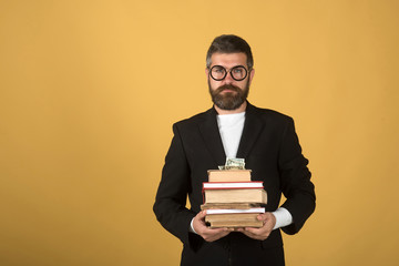 Teacher holds pile of books and money. Professor with beard