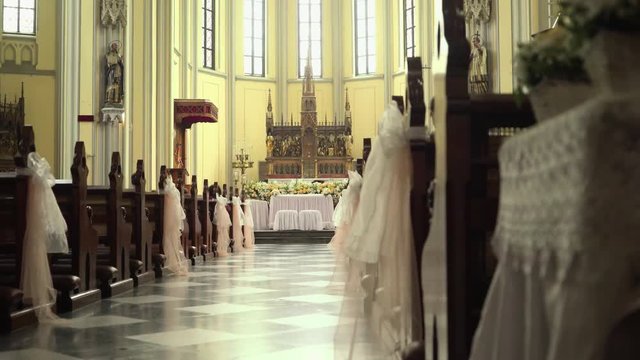 St. Mary of the Assumption Cathedral church interior decorated with flowers for wedding in Jakarta, Indonesia. Low angle dolly slide from behind bench. Shot with Sony a7s and Atomos Ninja Flame