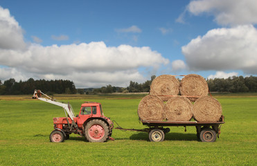 roter traktor mit heuballen auf anhänger