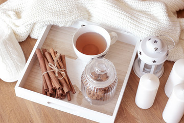 Home decor. Cup of hot tea, cookies in glass jar, comfortable slippers, knitted blanket. Warm winter. Cozy. 