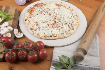 Margarita pizza surrounded with raw ingredients and a rolling pin 