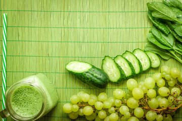 Ingredients for Green detox smoothie. Spinach, grape, cucumber on green background