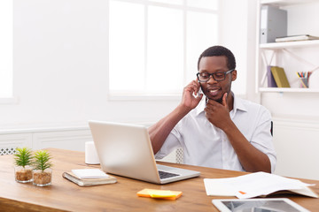 Young black businessman talking on mobile in modern white office