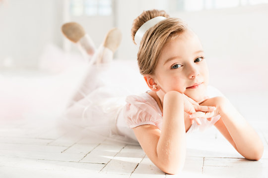The little balerina in white tutu in class at the ballet school